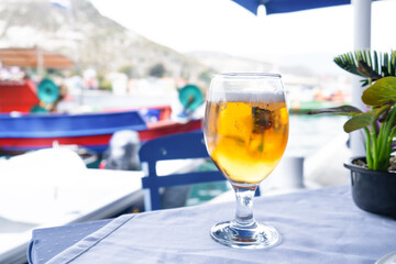 Glass of beer at table over a sea at background, Greece. Glass beer in a sea shore cafe. Close up...