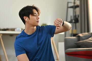 Fototapeta na wymiar Fitness young asian man checking pulse rate on smartwatch after morning workout. Healthy lifestyle and fitness concept