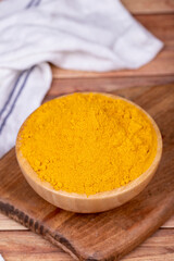 Powdered turmeric on wooden background. Dried ground turmeric powder spices in wooden bowl. Close up