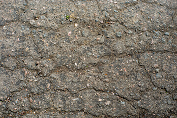 A network of black cracks on the asphalt surface. Road texture with weathered surface, showcasing the effects of time and wear