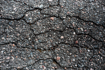 A network of black cracks on the asphalt surface. Road texture with weathered surface, showcasing...