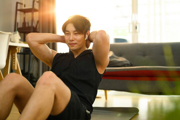 Strong asian man wearing sporty clothes doing sit up exercise during home workout. Sport, fitness and healthy lifestyle