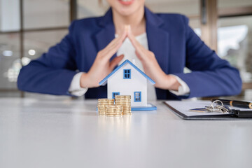 House model with real estate agent and customer discussing for contract to buy house, insurance or...