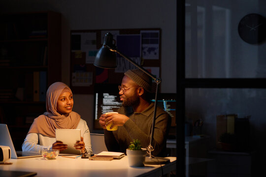 Young colleagues working together during deadline in office, they sitting at table and discussing online project