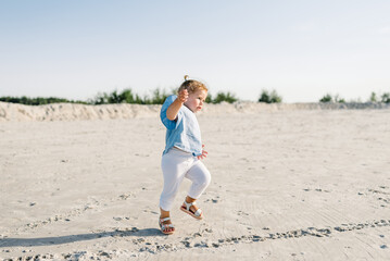Kid runs. Child baby walk on the sand on the sandy beach. Little girl toddler playing and walking in the sand. The concept of family summer vacation with children outdoors.