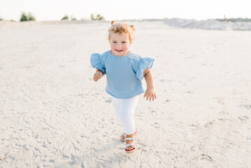 Child baby walk on the sand on the sandy beach. Little girl toddler playing and walking in the...