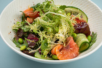 Portion of fresh gourmet salad with salmon on blue background