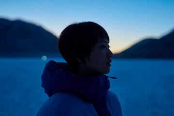夜明け前,冬の山にいるショートヘアの女性