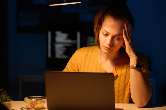 Young tired programmer working on computer in office till late night
