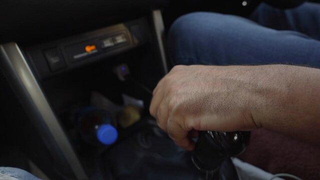 Close-up of male hand changing gear while driving an electric car
