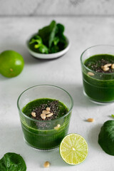 Green smoothie with spinach, banana, lime, chia seeds and pine nuts in a glass. Raw, vegan, vegetarian, healthy food concept