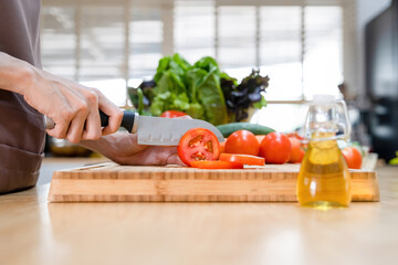 Woman cutting tomatoes on cutting board..