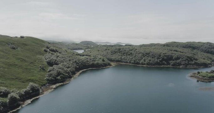 Slow pull back drone shot revealing a large body of water along the coastline in scotland looking out to sea and the Hebrides