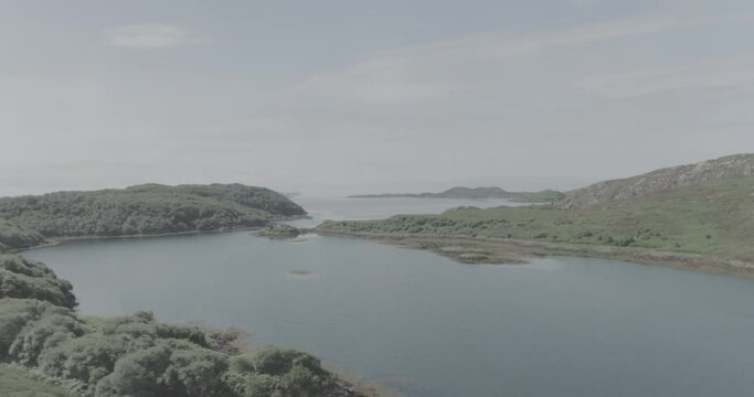 Panning drone shot revealing small islands in an estuary in Northern Scotland looking towards the Hebrides over the sea