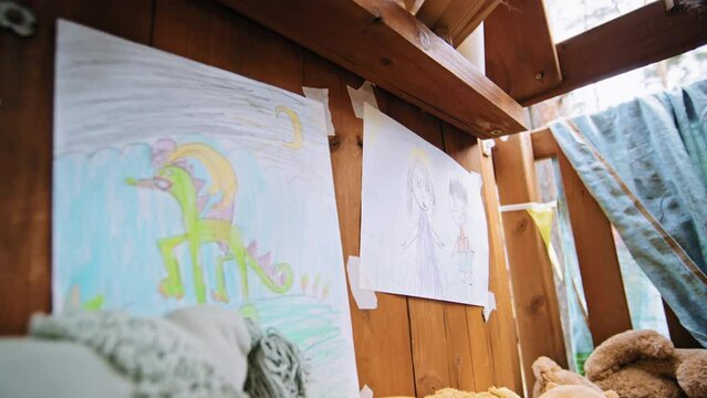Closeup of cute pencil pictures hanging on wall drawn by kids in treehouse at daytime