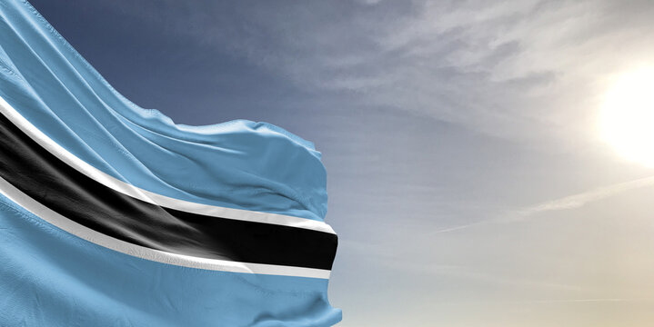 Botswana national flag cloth fabric waving on beautiful grey sky Background.