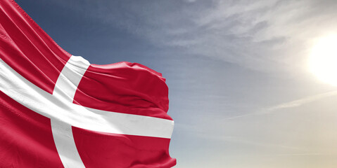 Denmark national flag cloth fabric waving on beautiful grey sky Background.