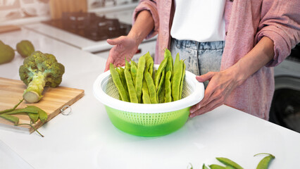 A Young woman stands in the kitchen at home and is going to cook a vegetarian diet food. The concept of a healthy nutrition and veggie lifestyle. Green vegetables and made meals at home