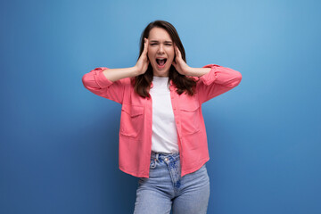 laughing brunette young woman in pink shirt and jeans on studio isolated background
