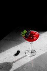 Blackberry Cocktail Blackberry Martini  with fresh berries, ice and mint. Refreshing alcoholic drink with blackberry and ice on a stone grey background. 