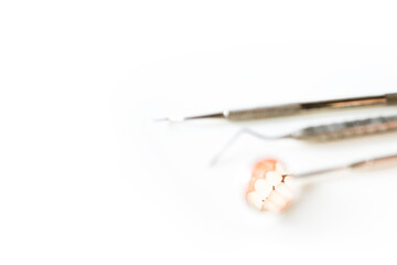 Dental mirror or instrument on white table with blur background and space.Tooth or teeth problem at dental clinic.Orthodontic and Dentistry concept.Dentist tool at clinic or hospital.Tooth extraction.