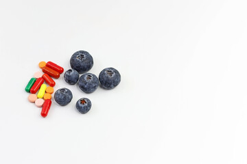 Blueberries next to pills or medications. Concept of alternative medicine. Urinary tract infections. Space for text