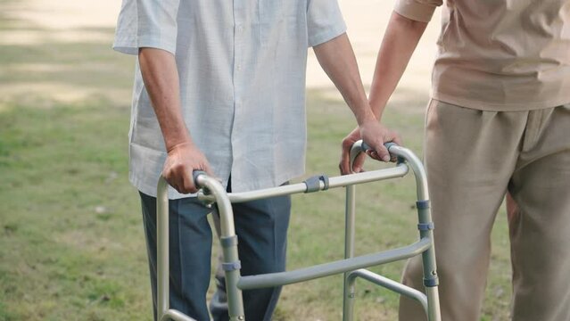 Asian senior woman help husband walking with walker cane in the garden, Take care concept