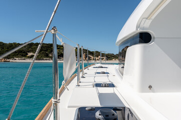 Fototapeta premium Deck of catamaran with metal railing floating in blue sea water on sunny day