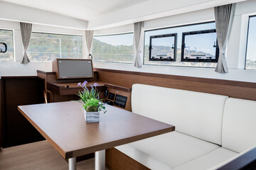 Luxury interior of dining room with sofa and wooden table in cabin of contemporary catamaran