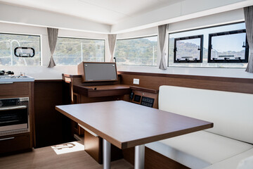Luxury interior of dining room with sofa and wooden table in cabin of contemporary catamaran
