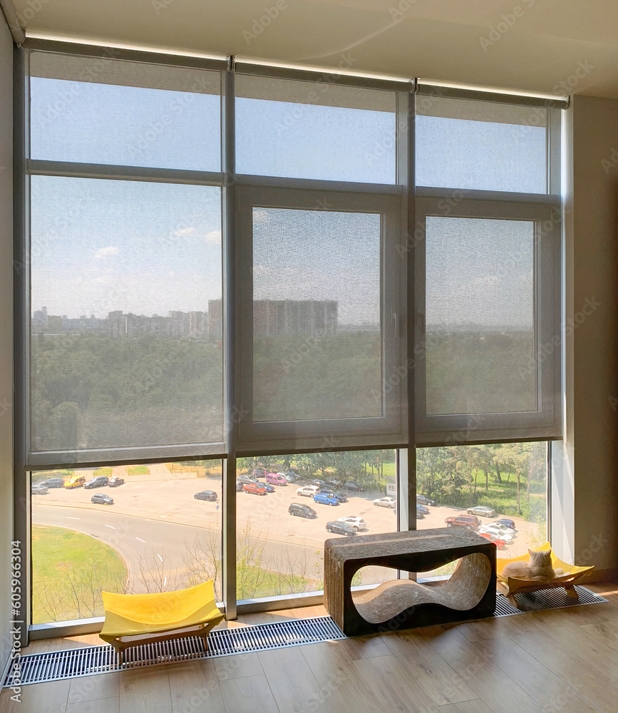 Poster roller blinds on the windows in the interior. automatic solar shades on full height windows. motoriz