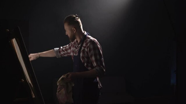 Professional male artist creating art painting in spacious dark workshop