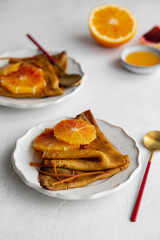 Traditional French Crêpes suzette pancakes with orange sauce on a serving dish on a light grey...