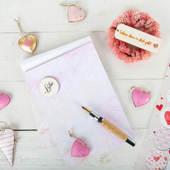 Einen Liebesbrief schreiben: Brief Block mit Füller und rosa Herzen auf Weiß