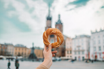 Young female tourist hand holding bagel, obwarzanek, pretzel. traditional Polish snack on Market Square in Cracow. Traveling Europe in spring. High quality photo. 