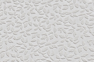 White paper wallpaper texture with abstract floral repeating pattern close up. Plastered embossed wall.