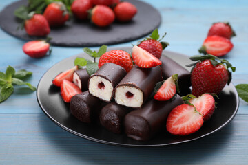 Delicious glazed curd snacks with fresh strawberries and mint on light blue wooden table