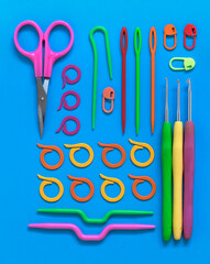 Bright colorful crochet and knitted tools on a blue background. Flat lay.