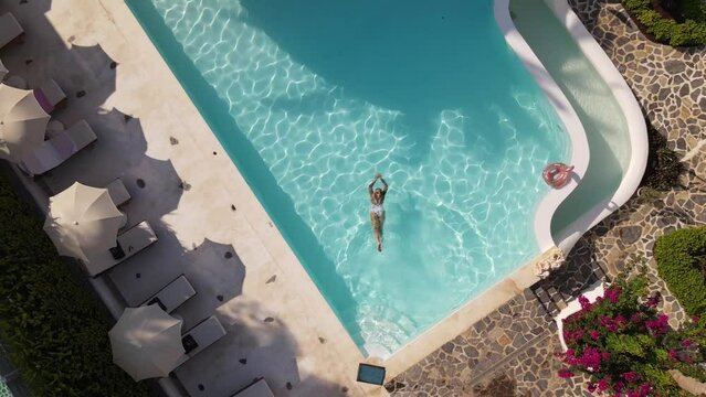Top view of woman swimming in hotel pool, summer time, drone footage, Turkey