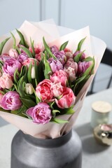 Vase with bouquet of beautiful tulips on table indoors, closeup