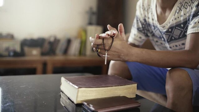 Hands folded in prayer with holding a cross on a Holy Bible in church concept for faith, spirituality and religion, man praying on holy bible in the morning. man hand with Bible praying.