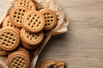 Tasty sandwich cookies with cream on wooden table, flat lay. Space for text