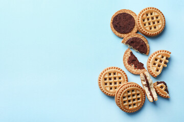 Tasty sandwich cookies with cream on light blue background, flat lay. Space for text