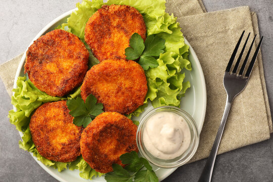 Tasty vegan cutlets served with sauce on light grey table, top view