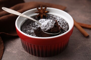 Tasty chocolate pie with anise and spoon on brown table, closeup. Microwave cake recipe