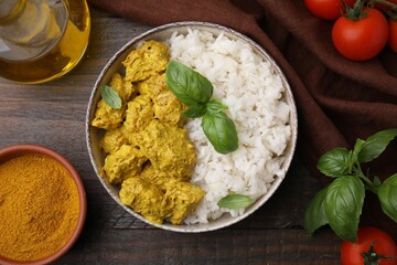 Delicious rice, chicken with curry sauce and products on wooden table, flat lay
