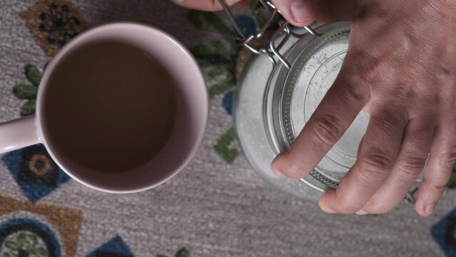 action hand of putting sugar in the morning coffee with milk
