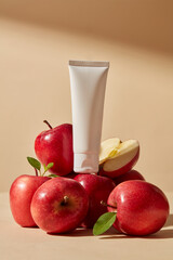 A stack of many apples with unlabeled white tube place on top. Container packaging of skin care branding extracted from Apple (Malus domestica)