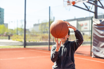 Naklejka premium A girl with basketball on court on summer season.