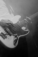 Close-up of bass guitar player in action in the stage fog. Black and white
